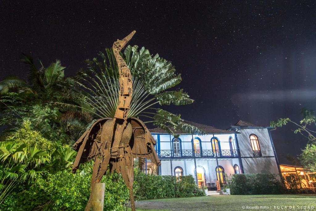The casa grande lit at night with a garden sculpture at Roça São João dos Angolares, São Tomé