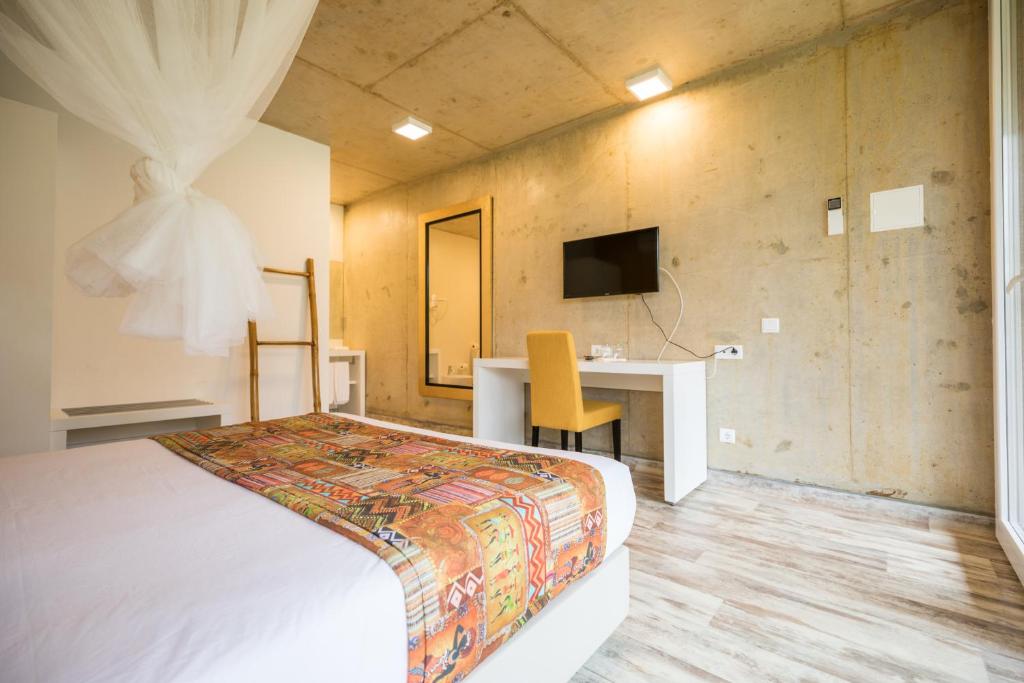 Guest room with a work desk and concrete-finish walls at Roça Santo António Ecolodge, São Tomé