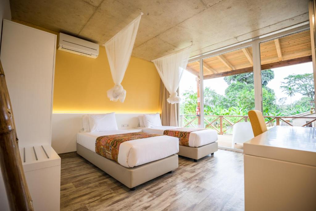 Twin guest room with a large garden window at Roça Santo António Ecolodge, São Tomé
