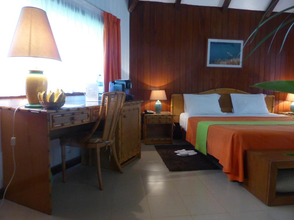 Bungalow bedroom with work desk and sea-life artwork at Club Santana, São Tomé
