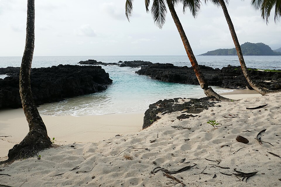 Sandy cove with black lava rock and palms on Ilhéu das Rolas