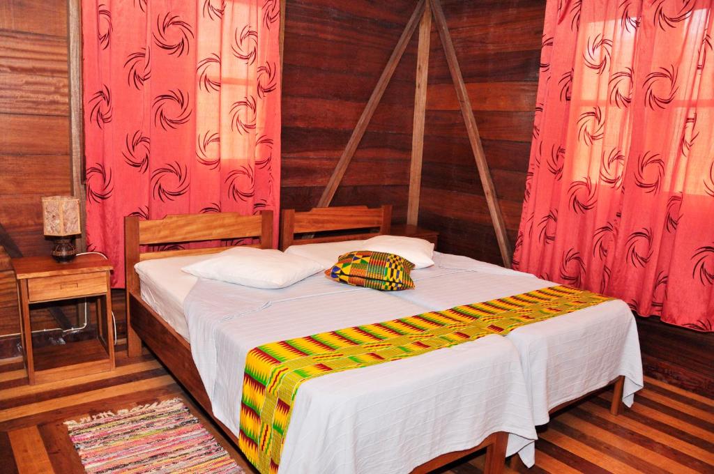 Wooden chalet bedroom with kente textiles at Praia Inhame Eco Lodge