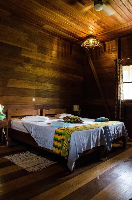 Timber-walled bedroom with double bed at Praia Inhame Eco Lodge