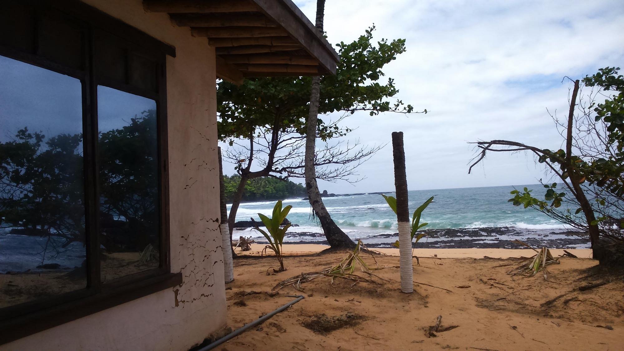 Bungalow window framing the ocean and rocky shore at Jalé Ecolodge