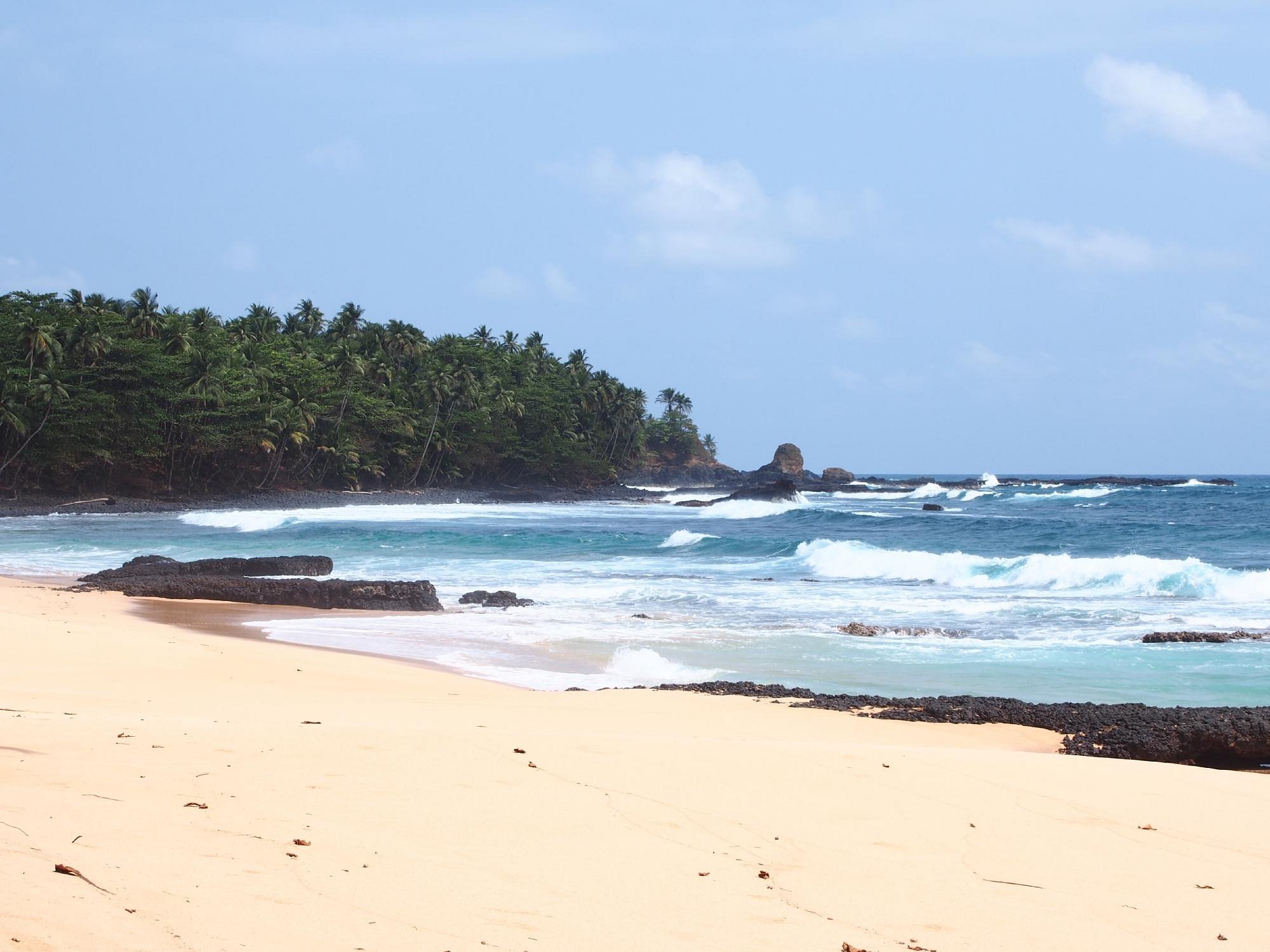 Wild golden-sand beach with volcanic rocks and surf below Jalé Ecolodge