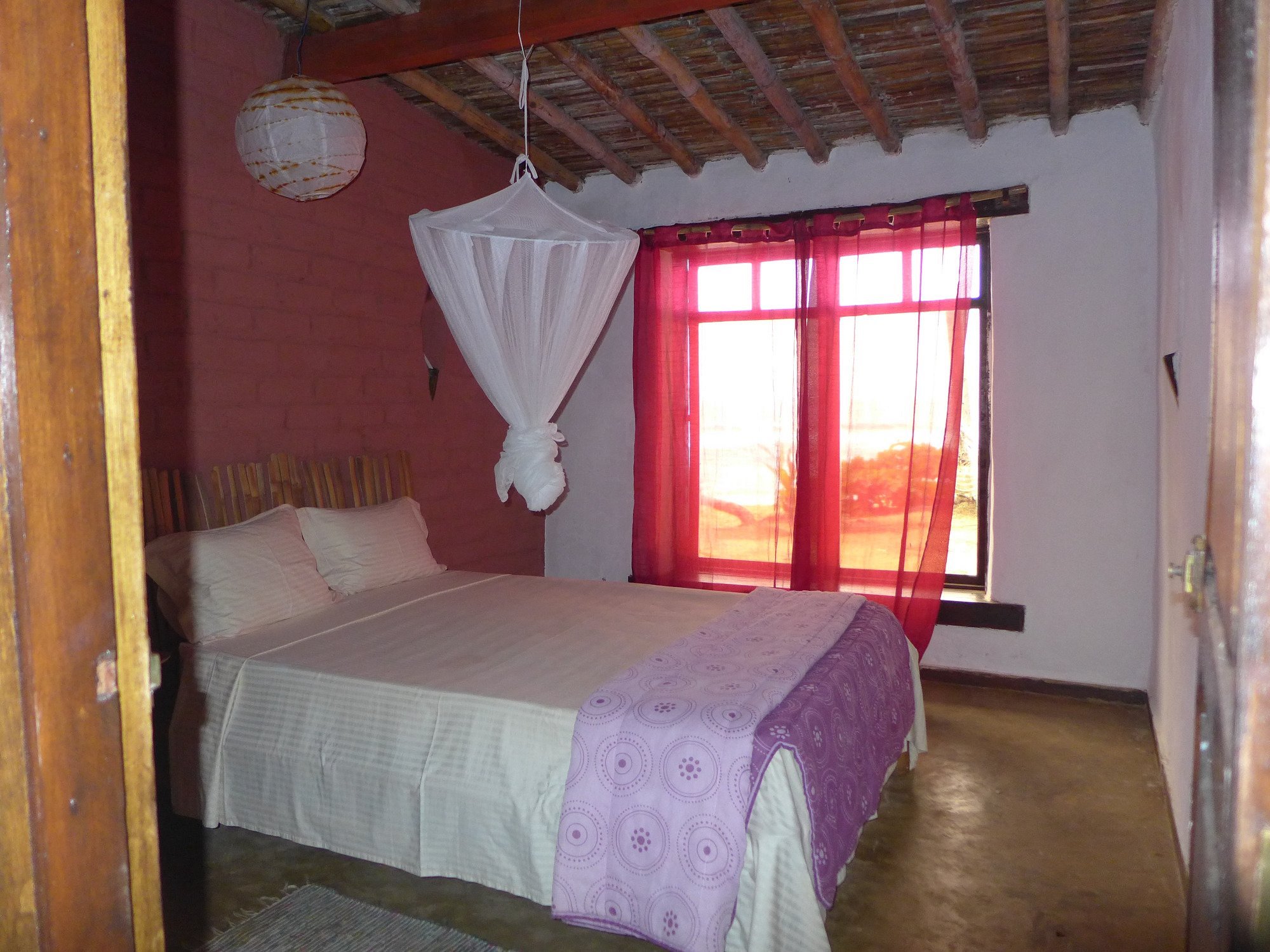 Simple bungalow bedroom with mosquito net at Jalé Ecolodge